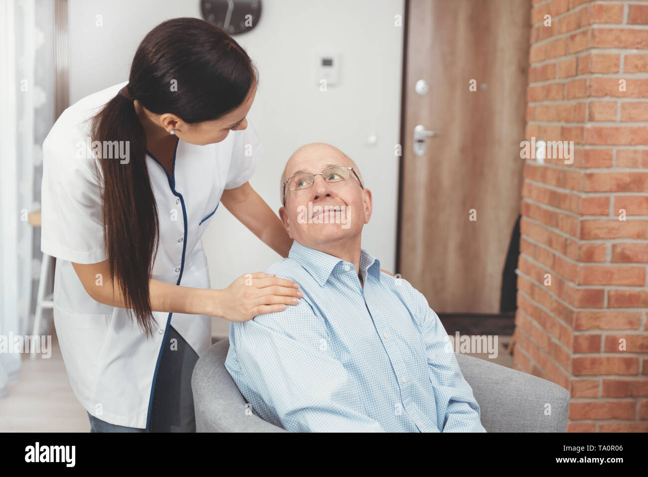 Smiling nurse and old senior man patient at home. Care for older people concept Stock Photo