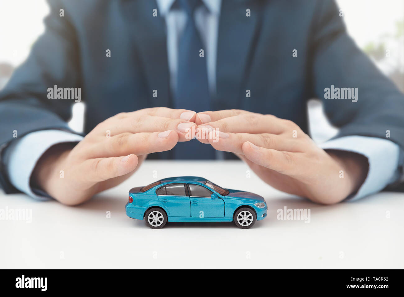 Car insurance, protection and safety concept. Insurance agent protects car with hands. Stock Photo