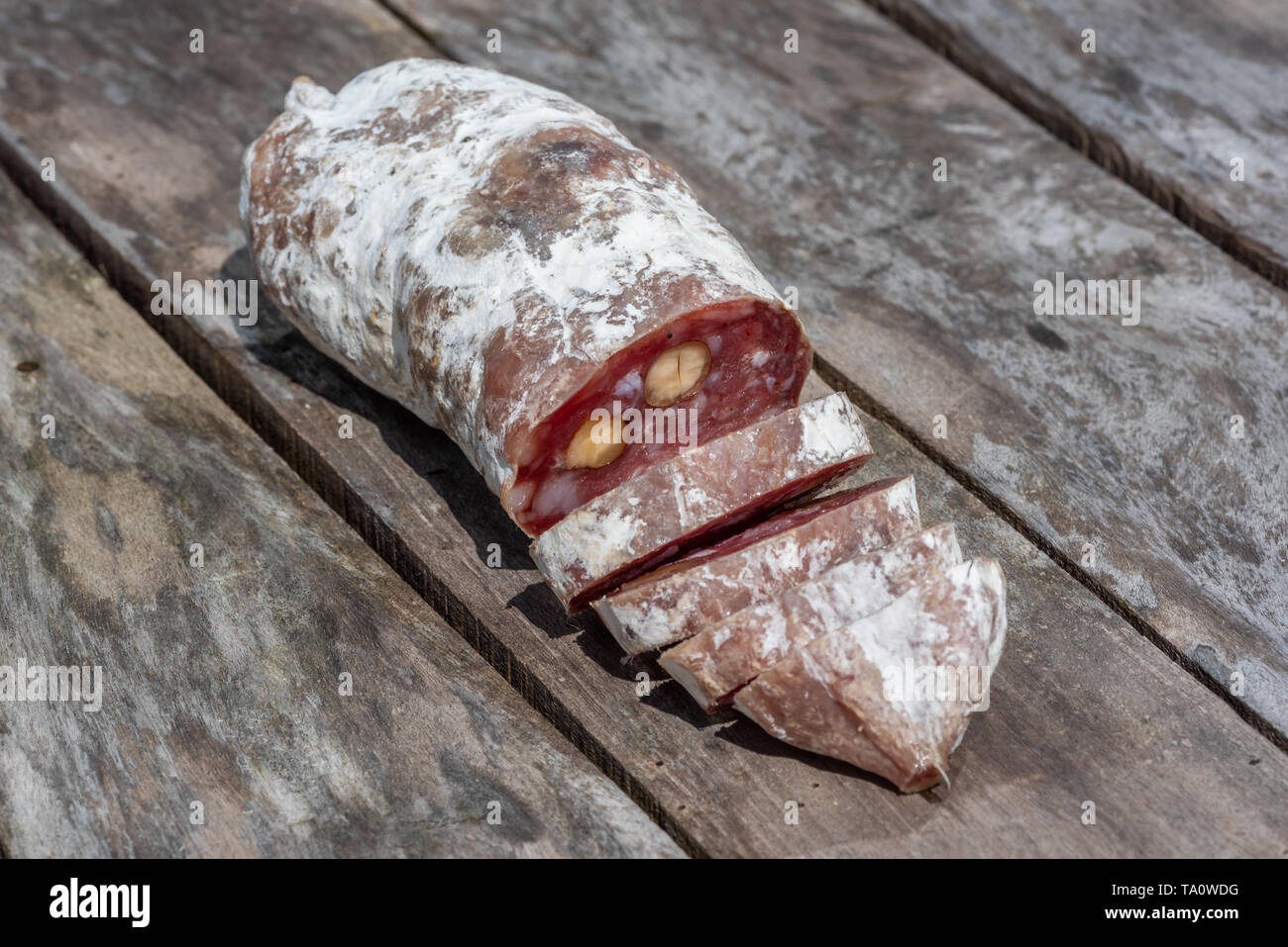 Dried sausage with nuts cut in slices close-up view on a wooden table Stock Photo