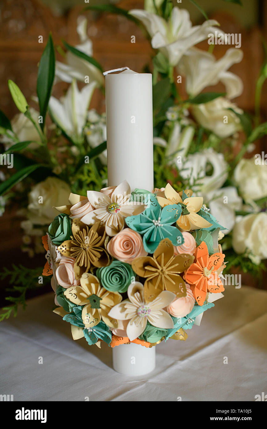 Baptismal candle with a round paper bouquet in an Orthodox church in preparation for the baptism, first of seven Sacraments in the Orthodox Church Stock Photo