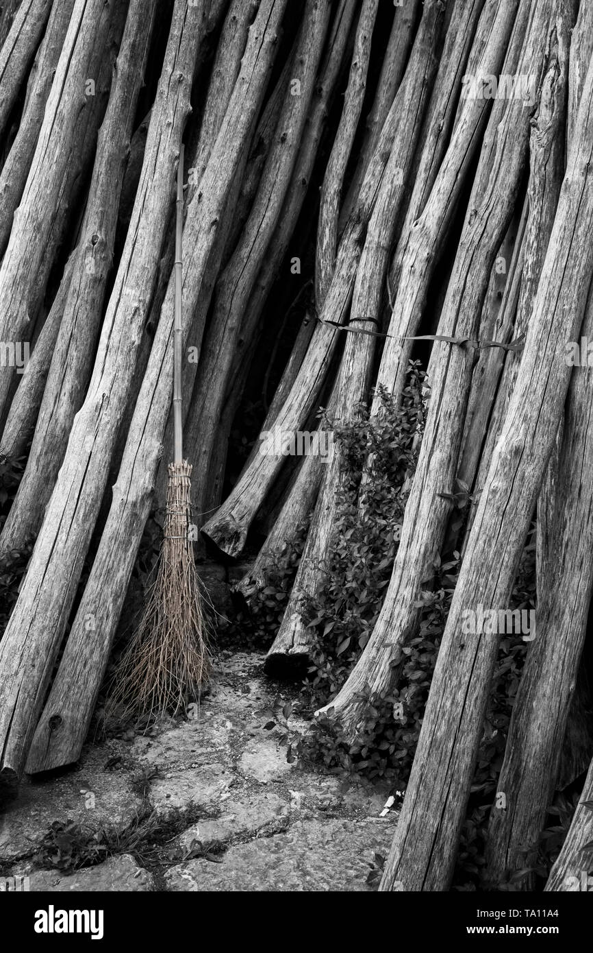 Desaturated image of a besom broom - traditional  birch broom or witches broom leaning against a stack of timber Stock Photo