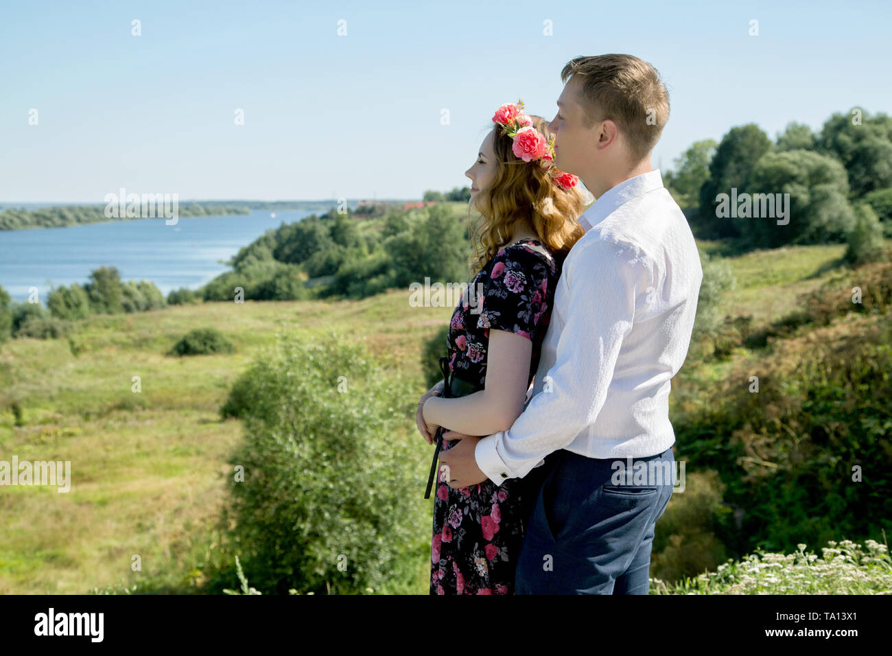girl and boy hugging on a high bank of the river on a summer day Stock Photo
