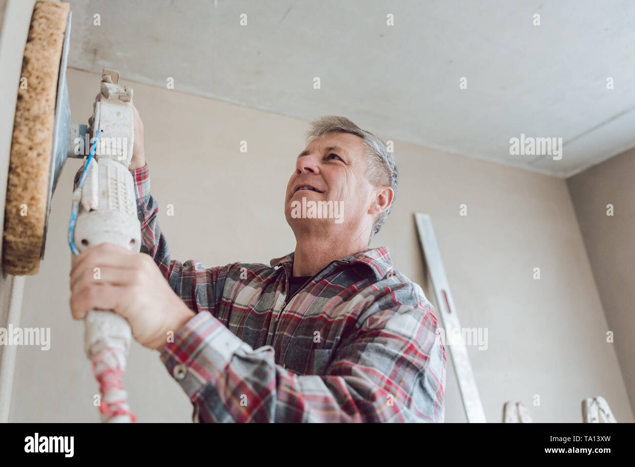Plasterer smoothing interior wall with machine Stock Photo