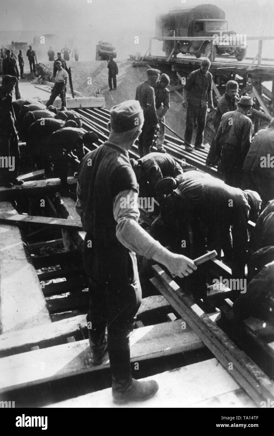 Frontline workers of the Todt Organization are buliding a bridge with iron girders on the Eastern Front in the Soviet Union. War reporter: Maier. Stock Photo