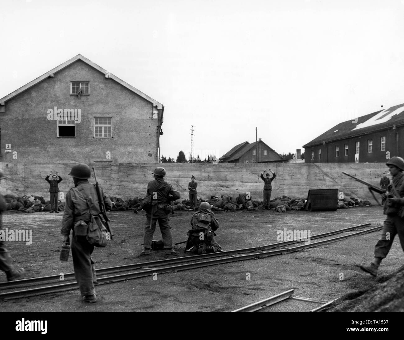 Soldiers of the 157th Infantry Regiment of the US Army are targeting SS men, who are lined up along a wall. According to the original caption, the SS men lying on the ground try to pretend to be dead after the Americans opened fire on a fleeing guard. In a spontaneous revenge action between 39 and 50 guards were shot and this photo shows probably the moment before the execution. Stock Photo