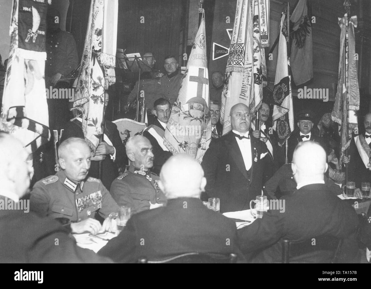 Highly decorated officers and members of the Kriegserverein Friedenau, appearing in civilian clothes, celebrate a foundation anniversary with flags in the background, in the Victoriagarten in the Wilmersdorf district of Berlin. Stock Photo