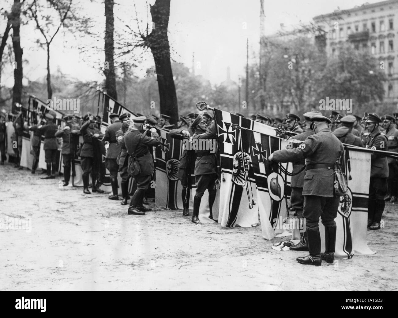 On the occasion of the reintroduction of military service and the revision of the Treaty of Versailles, the black ribbons are removed from the flags of the National Socialist Alliance of Red Front-Fighters during a parade at the Jahnsportplatz in the Volkspark Hasenheide, Berlin. Stock Photo