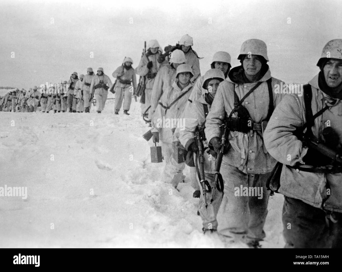 During the winter defensive battles on the Eastern Front, German soldiers march across a snow-covered field. Photo of the Propaganda Company (PK): war correspondent Wacker. Stock Photo