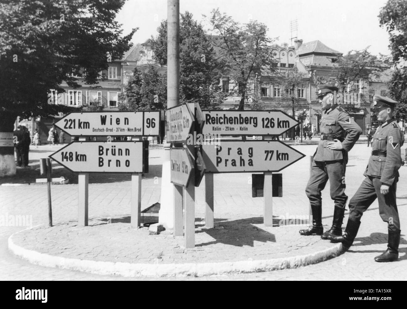 Soldiers of the Wehrmacht observe at the street signs, which are in German and Czech. Since March 1939, the territories of Bohemia and Moravia had been under German occupation. Stock Photo