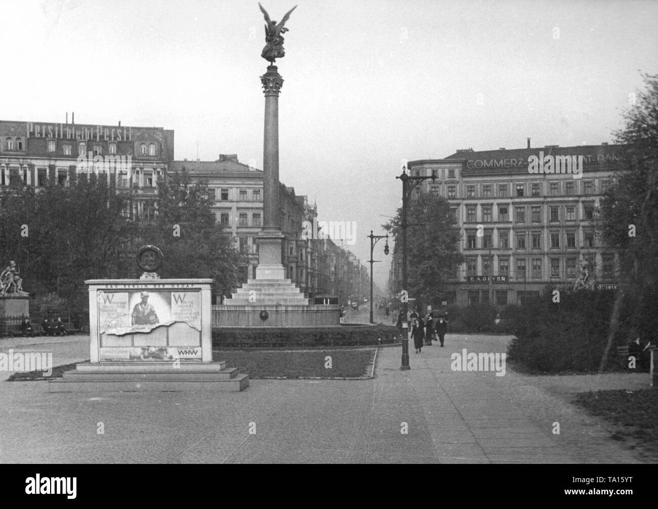 View of the Belle-Alliance-Platz (today's Mehringplatz) with the Friedenssaeule in Berlin. In the background the Friedrichstrasse. Left the Friedrichstrasse facade advertising of Persil, right of the Commerz - und Privatbank. In front of the Friedenssaeule, partly torn-down posters hang on a notice board of the Gau Berlin with the morale-boosting slogans: 'When we think of the sacrifices of our soldiers, their dedication, then every sacrifice of the homeland is utterly meaningless and insignificant' and 'What the homeland achieves must some day withstand the test of history'. Stock Photo