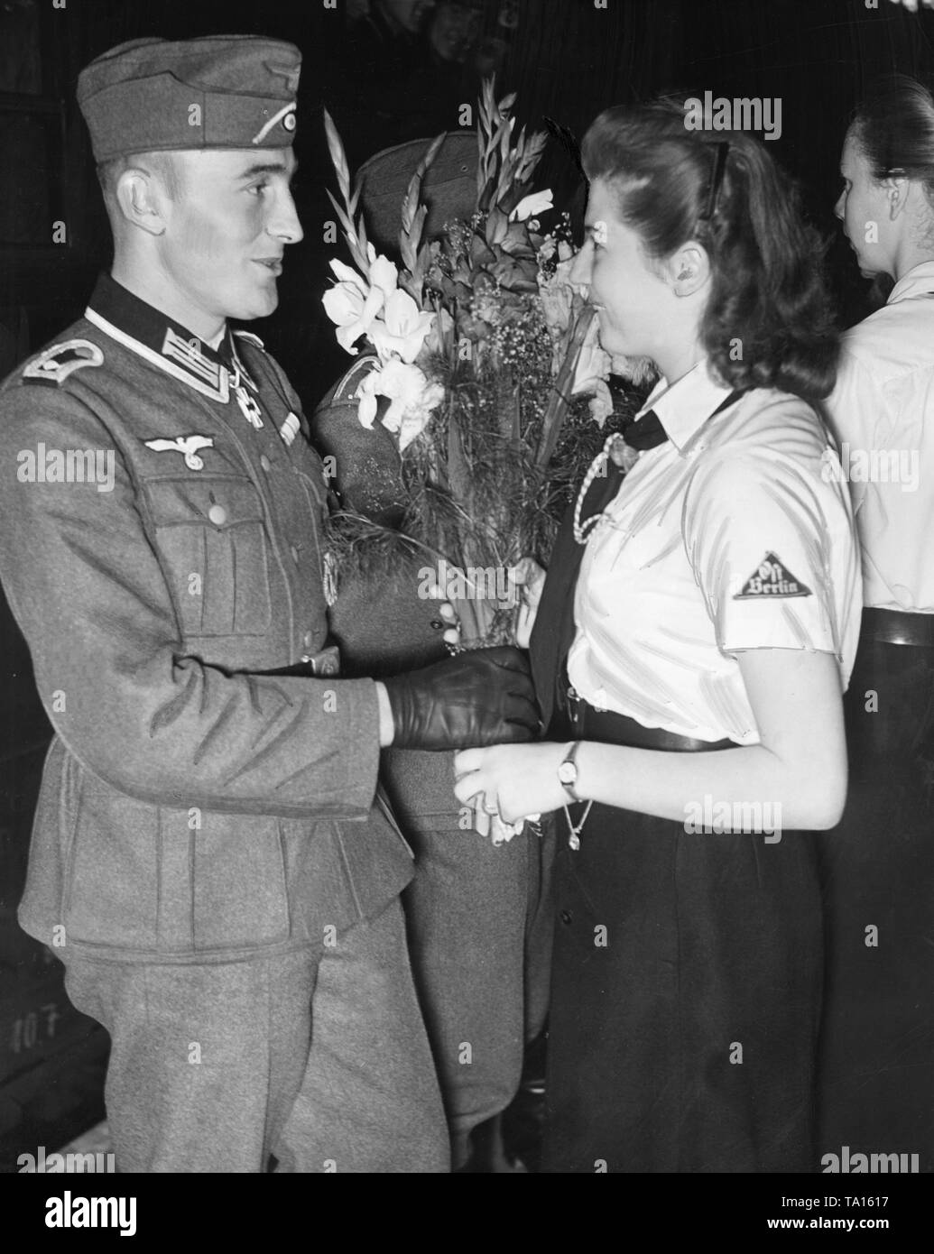 A BDM leader hands over a bouquet of flowers to a returned soldier from the Crimea, who was awarded the Knight's Cross. Stock Photo