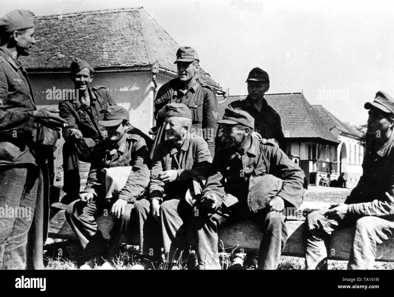 German soldiers have a conversation in a village in the Carpathians. Presumably, they are men, who were previously captured by the Red Army, and they managed to escape. Photo of the Propaganda Company (PK): War correspondent Waidelich. Stock Photo