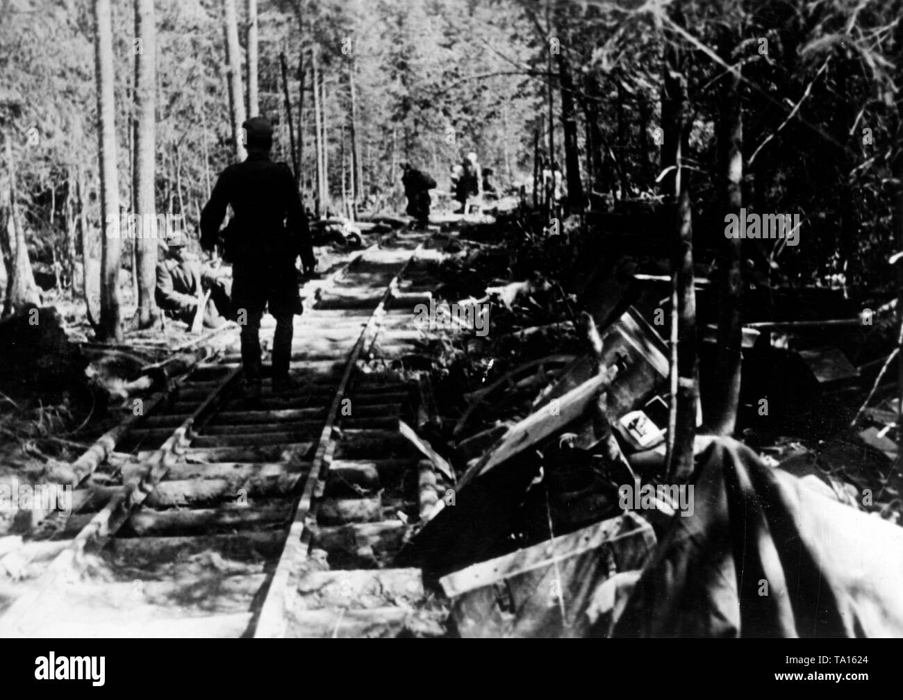 German soldiers walk along light railway tracks. On the left and right, destroyed material and weapons. Photo of the Propaganda Company (PK): war correspondent Rutkowski. Stock Photo