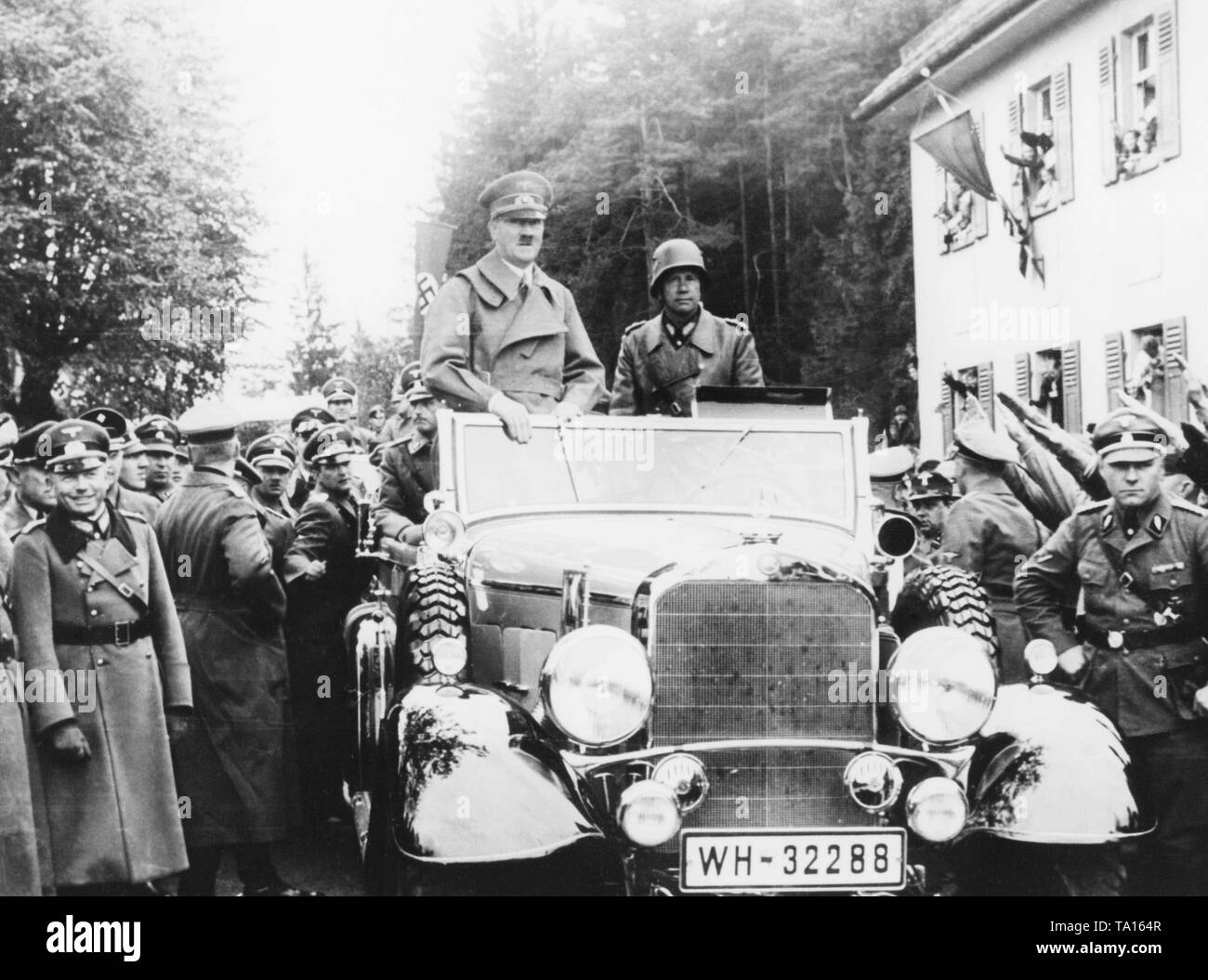 Adolf Hitler entering a city in the occupied Sudetenland. Hitler's motorcade is received by the cheering population. They are greeting him with the Nazi salute. With Hitler in the car, General Walter von Reichenau. On the left side of the road, General of the Armored Corps Heinz Guderian. Stock Photo