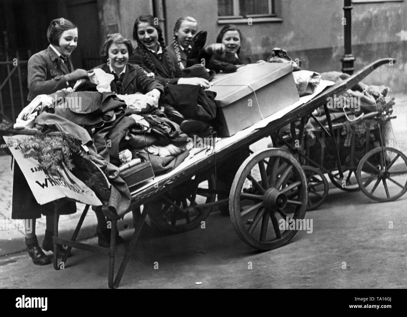 Members of the Bund Deutscher Maedel collect clothes with a handcart for the NS-Winterhilfswerk. Stock Photo