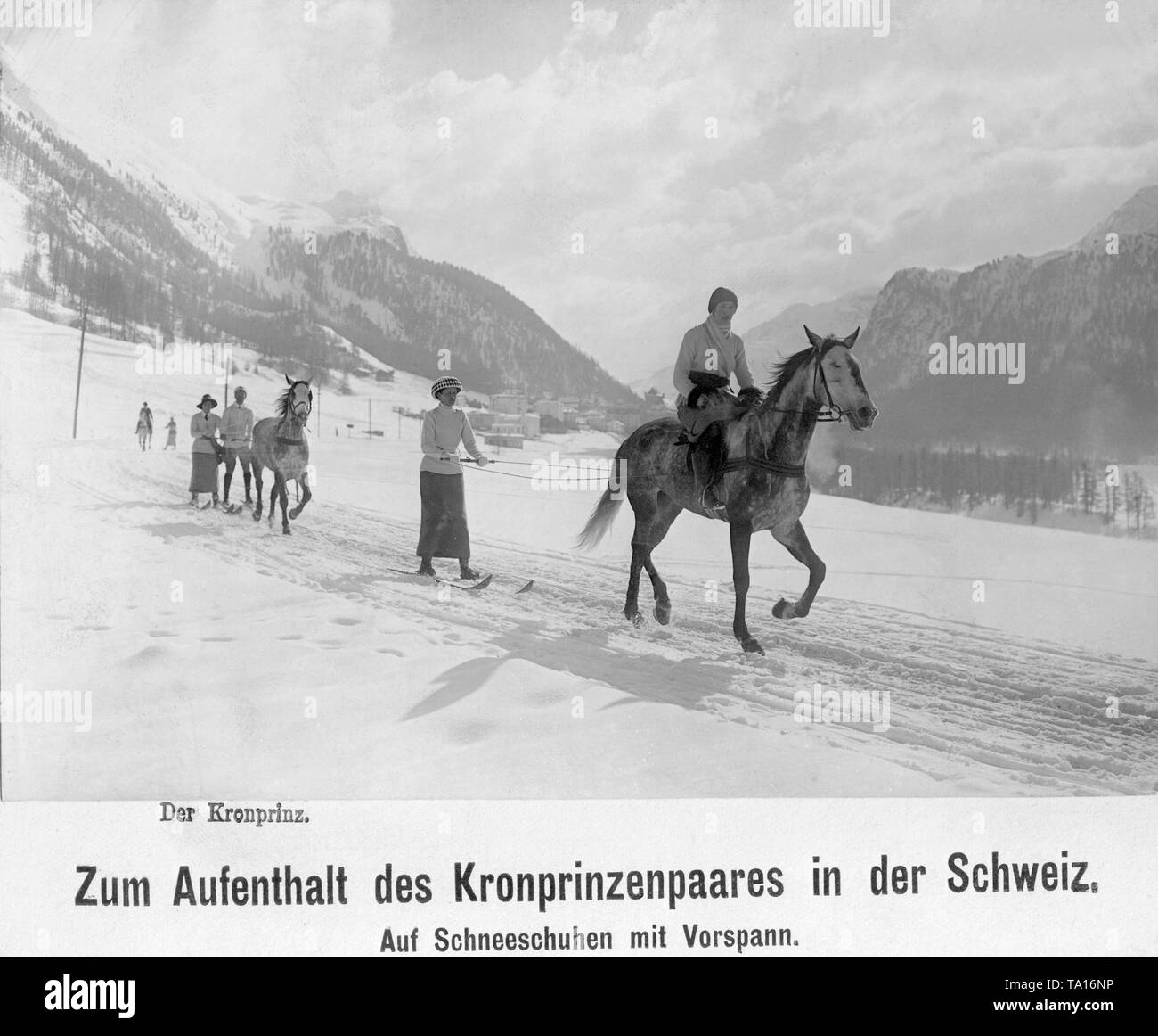 Crown Prince Wilhelm of Prussia (behind the second horse at right) and his wife Cecilie (left next to her husband) doing winter sports in Switzerland. The two are wearing skis and are pulled through the winter landscape by a horse. Stock Photo