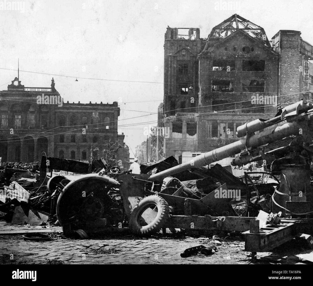 The Potsdamer Platz in Berlin after the capture of the city by the Red Army. On the right, a destroyed 8.8 cm FlaK 18/36/37, which, until recently, was used in the fight against Soviet tanks. In the background a group of civilians in front of Russian road signs. Stock Photo