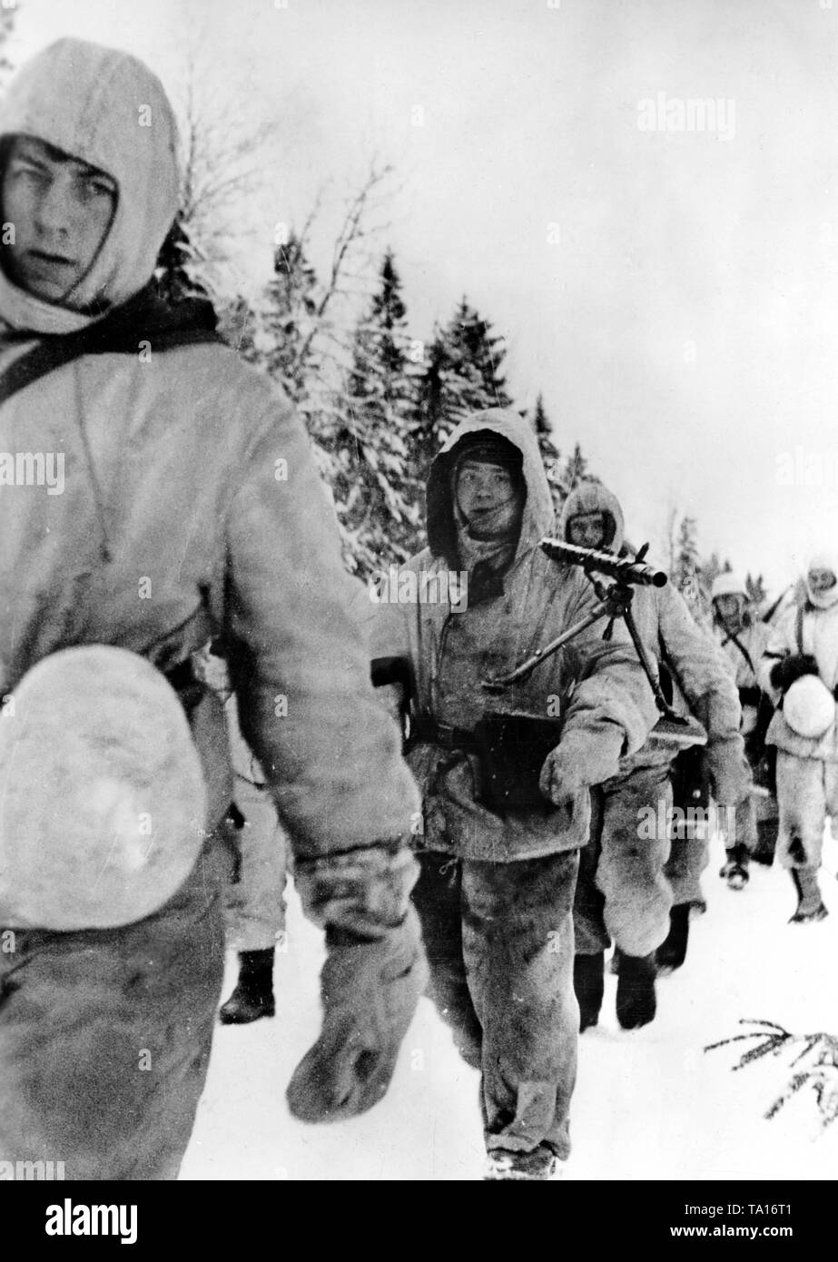 German soldiers march across a snow-covered field during the winter defensive battles on the Eastern Front. Photo of the Propaganda Company (PK): war correspondent Wacker. Stock Photo