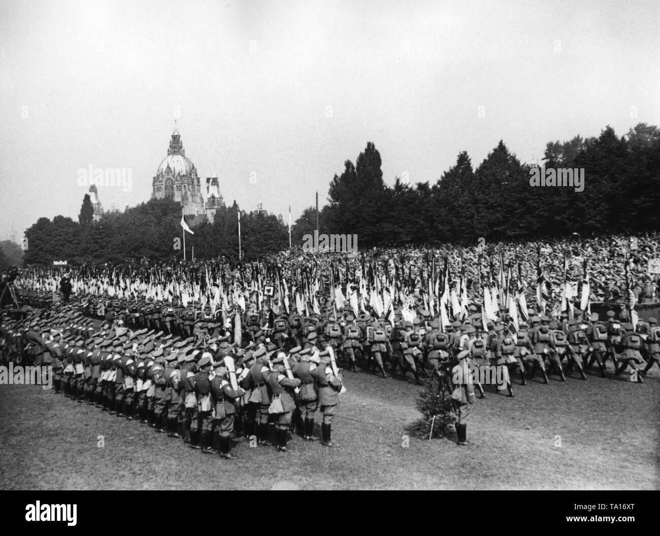 The flagbearers of the Stahlhelm are marching by SA Stabchef (chief of staff) Ernst Roehm (on the right), at a Reich leadership meeting at the Maschsee in Hanover. On the left, a brass band. In the background, the New Town Hall. Stock Photo