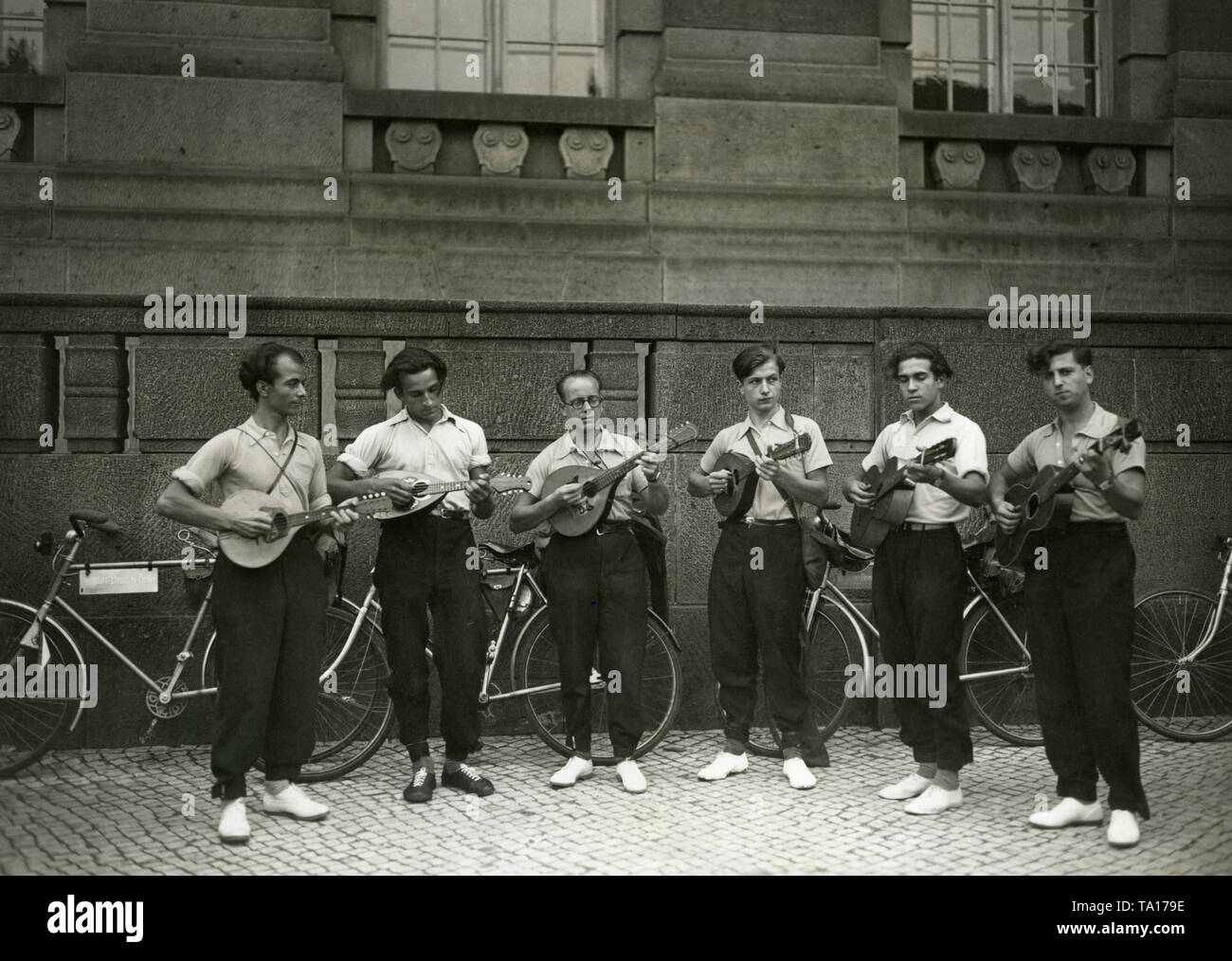 Six unemployed men are playing the guitar and mandolin in Berlin-Friedenau shortly before their departure to India. The men want to travel from Berlin via Lyon, Gibraltar, Morocco, Egypt, Arabia and Persia to Bombay within two years. Stock Photo