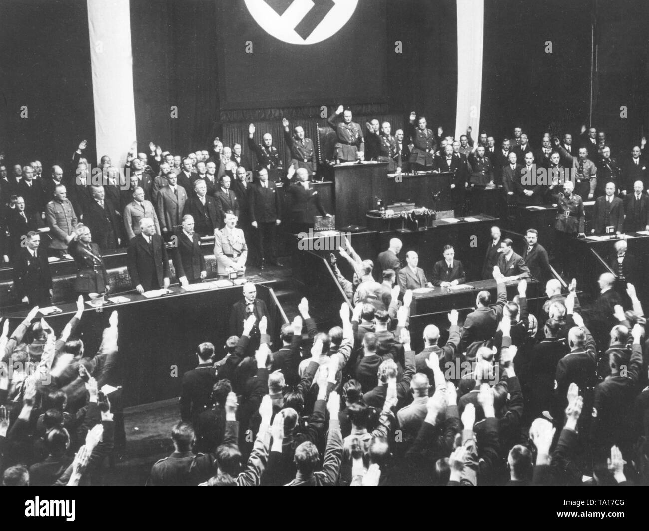 After Hitler's speech on the armament, the members of the assembly sing the national anthem and show the Nazi salute. On the government benches: Finance Minister Johann Ludwig Graf Schwerin von Krosik, Interior Minister Wilhelm Frick, Foreign Minister Konstantin Freiherr von Neurath, Vice Chancellor Franz von Papen and Adolf Hitler (front row from left) and Defense Minister Werner von Blomberg, Minister of Justice Franz Guertner , Labor Minister Franz Seldte and Economics Minister Alfred Hugenberg (rear row from left to right). As President of the Reichstag: Hermann Goering. Stock Photo