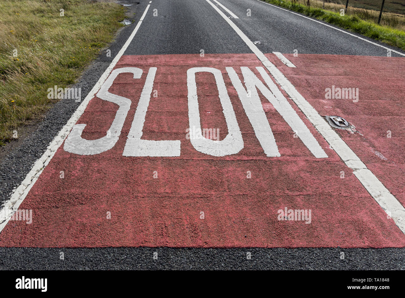 Slow warning sign written on the road in England. Slow road marking Stock Photo