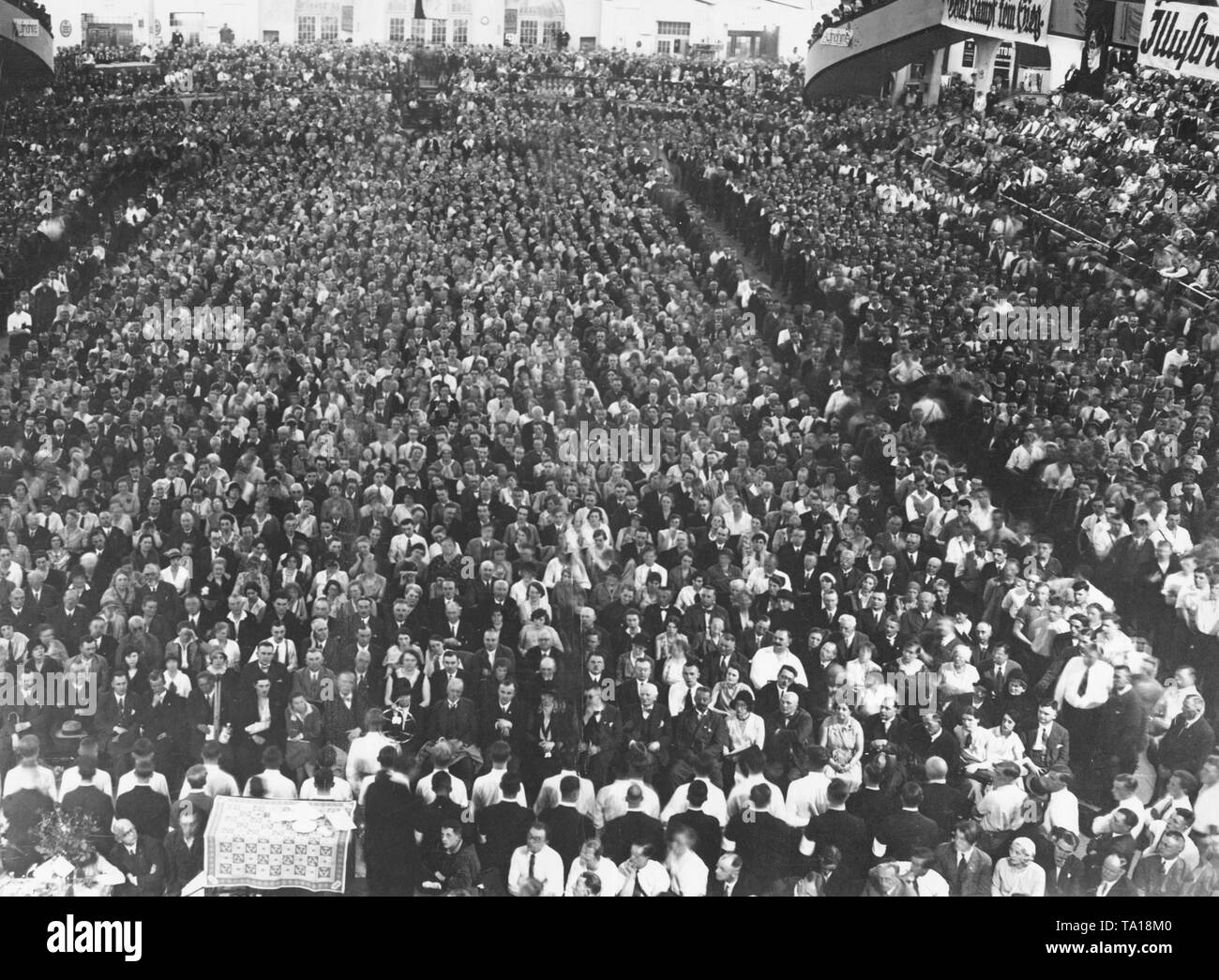 Adolf Hitler speaks in front of spectators at a meeting of the NSDAP, here an overview of the crowd. At the lower edge of the picture the SA men are recognizable by their white upper shirts, which they wear because of the uniform ban. Stock Photo