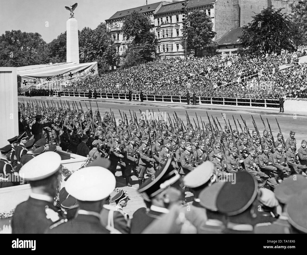 Photo of an infantry unit of the Condor Legion marching in front of officers of the Wehrmacht and leader, Adolf Hitler (under a canopy), on the East-West Axis (former Chalottenburger Chaussee, today Strasse des 17. Juni ) in front of the Technische Universitaet on June 6, 1939. Stock Photo