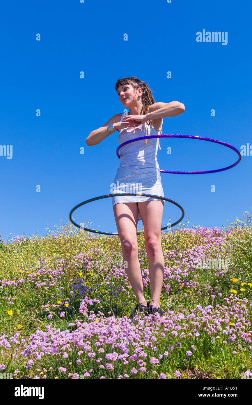 Southbourne, Bournemouth, Dorset, UK. 21st May 2019. UK weather: lovely warm sunny morning as Lottie Lucid performs her hula hooping routine on the seafront cliffs at Southbourne among the wildflowers, Sea Thrift, Armeria maritime, enjoying the warm sunny weather in her mini dress. Credit: Carolyn Jenkins/Alamy Live News Stock Photo