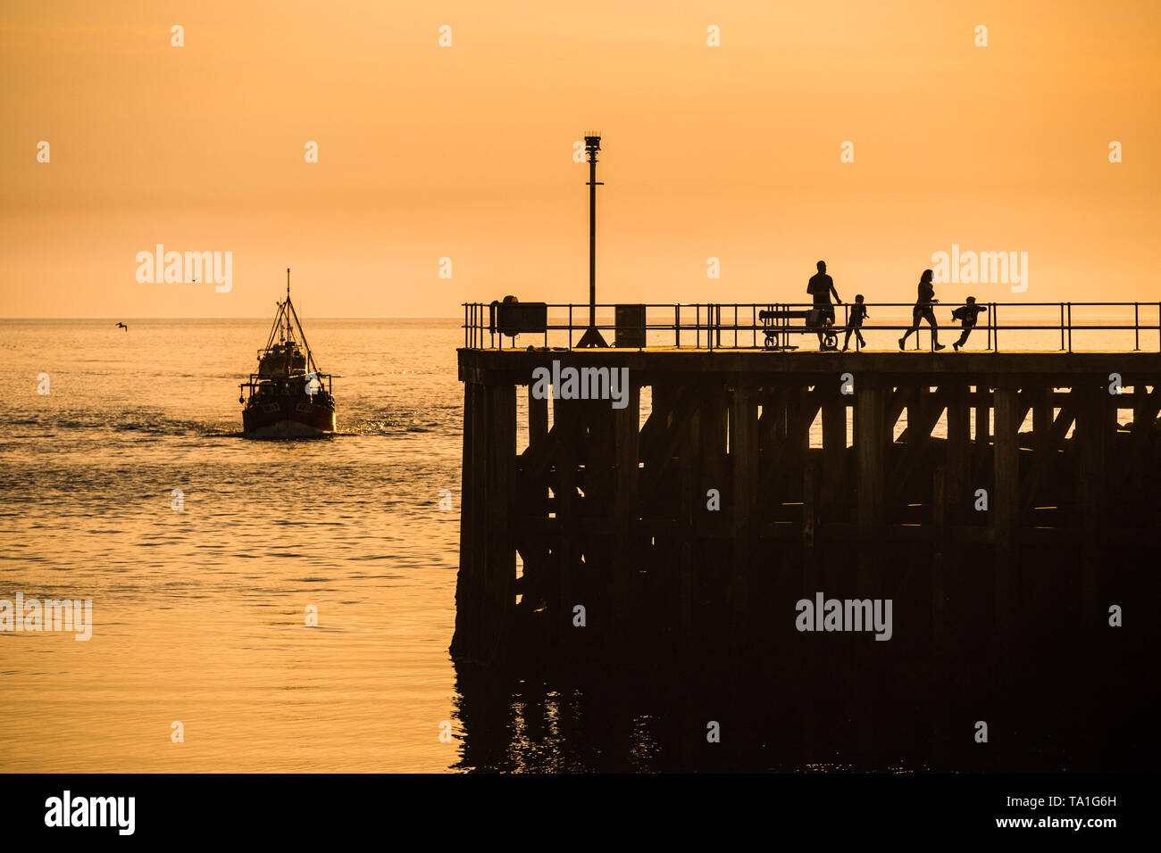 Aberystwyth Wales Uk. Tuesday 21 May 2019  UK weather: Inshore fishing boats are silhouetted as they return to Aberystwyth harbour with the high tide in the evening after a day out catching Cardigan Bay crab and lobster.   photo Credit: Keith Morris/Alamy Live News Stock Photo