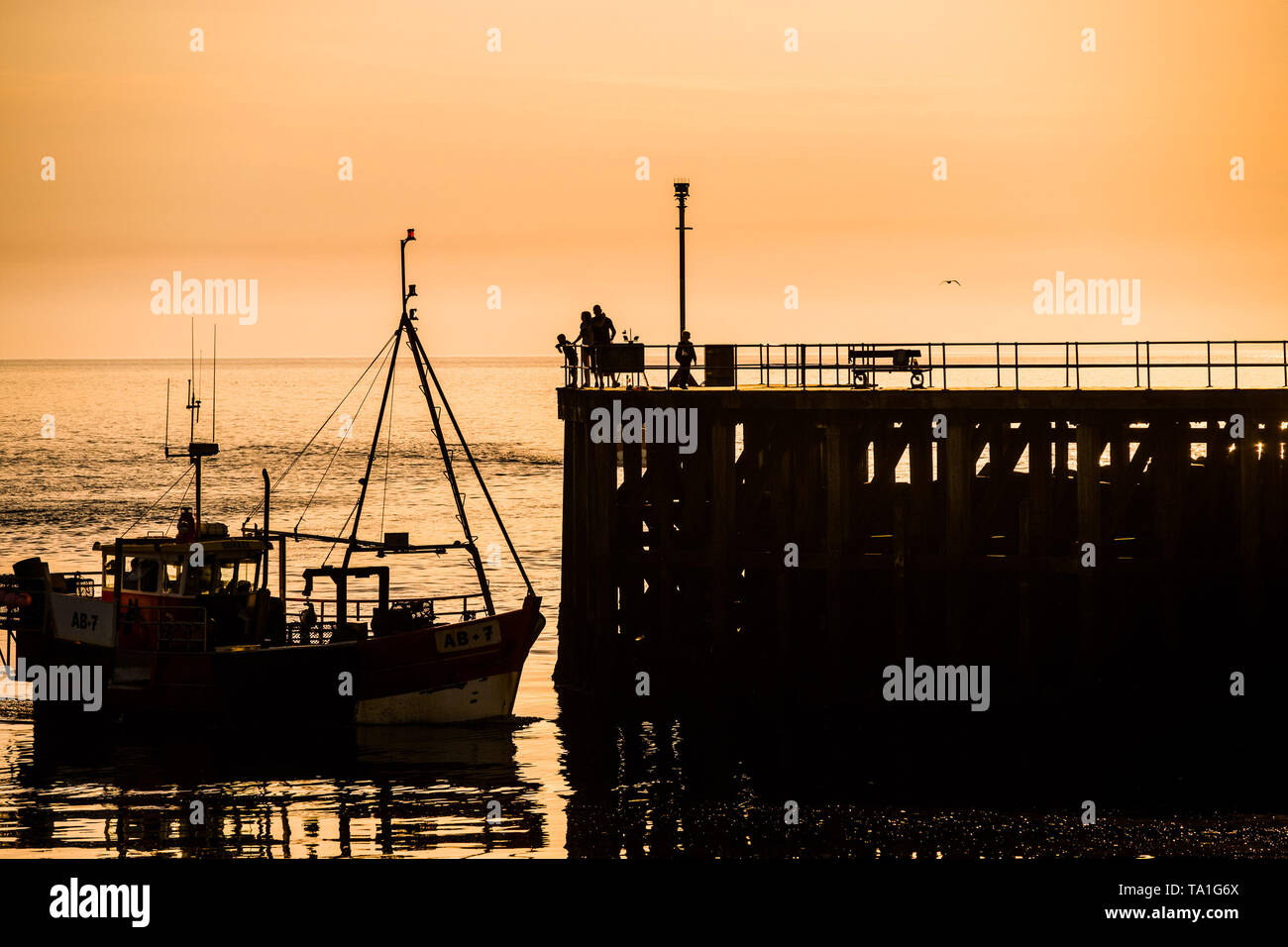 Aberystwyth Wales Uk. Tuesday 21 May 2019  UK weather: Inshore fishing boats are silhouetted as they return to Aberystwyth harbour with the high tide in the evening after a day out catching Cardigan Bay crab and lobster.   photo Credit: Keith Morris/Alamy Live News Stock Photo
