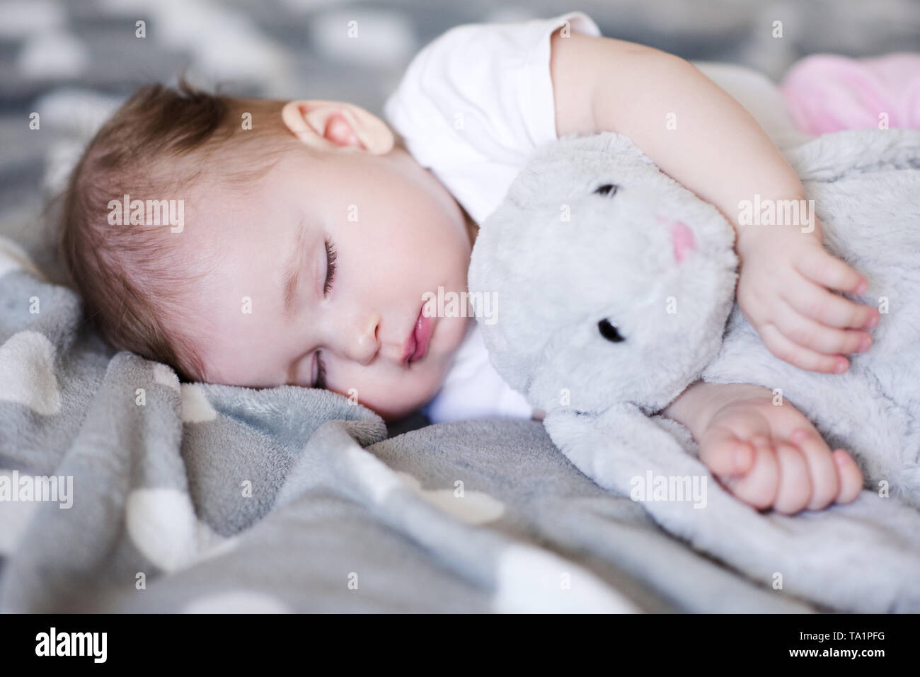 Cute baby sleeping with rabbit toy in bed close up. Good morning ...