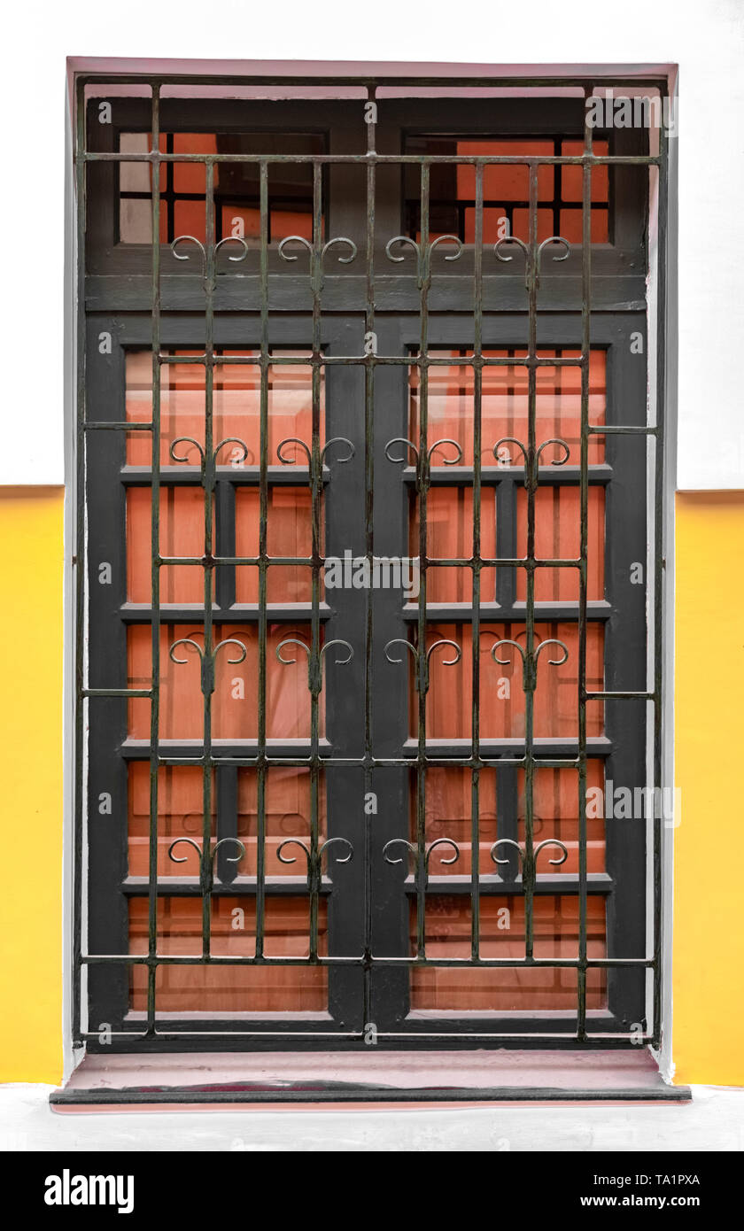Very Beautiful Corinthian Style Big Window, having Iron Bars with patterns and Wooden Gate attached to it. A Typical Colonian Era Roman Architecture. Stock Photo