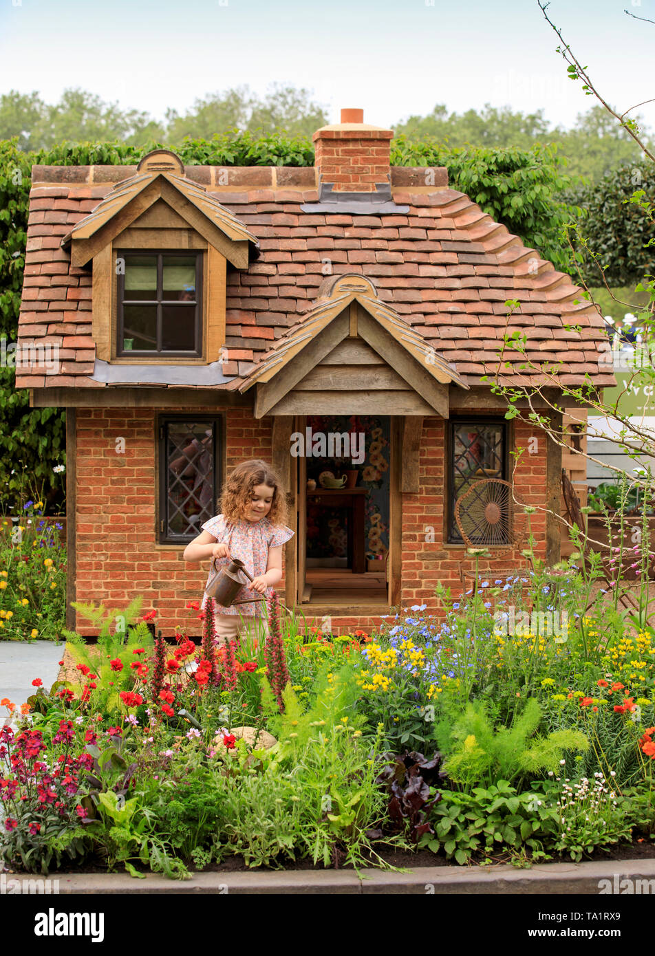 Rose Charlton age 4, from Hampshire, pictured adding the finished touches  to the garden in front of a cottage playhouse this morning at RHS Chelsea  Flower Show. Two beautiful bespoke playhouses are