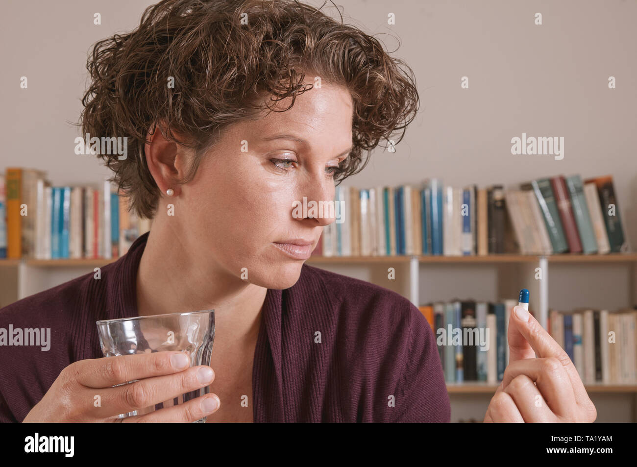 Young woman worried about taking pill Stock Photo