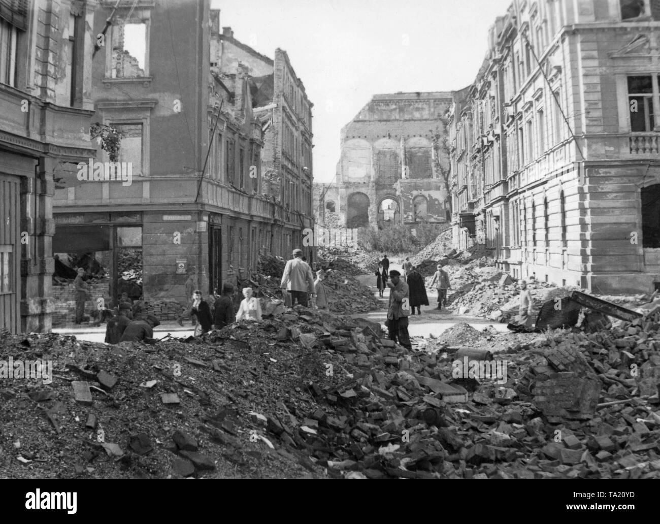 People cleaning up rubble after an Allied bombing at the intersection Schellingstrasse Schraudolphstrasse in Schwabing, Munich. In the background the destroyed Neue Pinakothek. Stock Photo