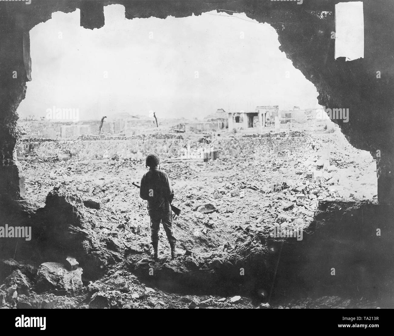 Back view of an American Soldier in a ruined house in the capital of Okinawa, Naha, 1945 Stock Photo