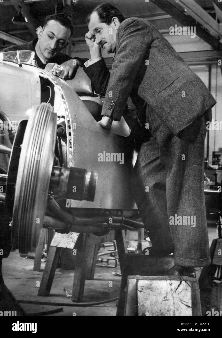 Prof Dr. H. C. Ferdinand Porsche with his mechanic Melzer at a racing car model that was built for Auto Union. Stock Photo