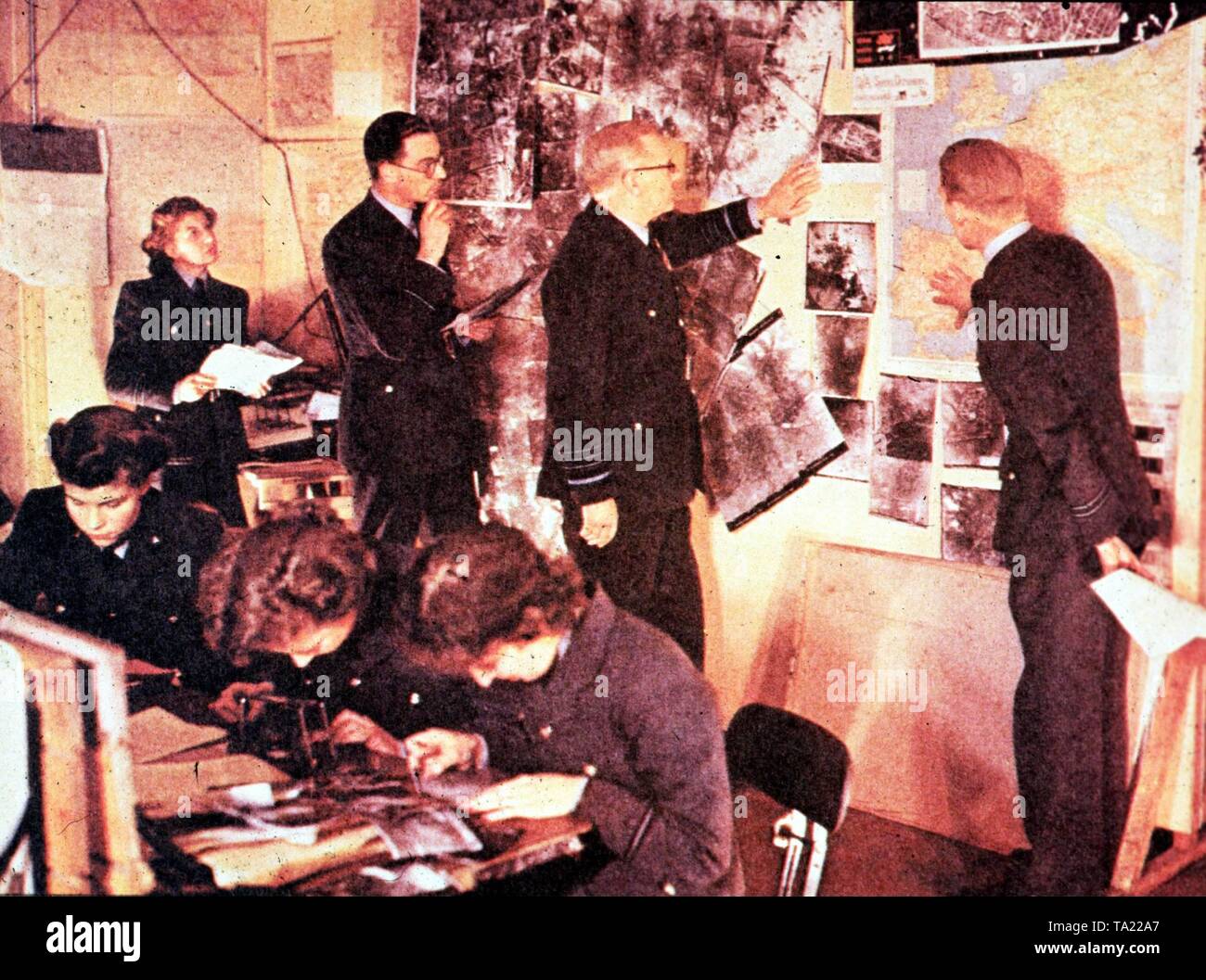 Command center of Air Marshal Arthur Harris, the strategic director of Allied air raids on Germany. The Air Marshal (center with glasses) in the evaluation room when evaluating of aerial photographs of bombed German cities in the 1944. Stock Photo