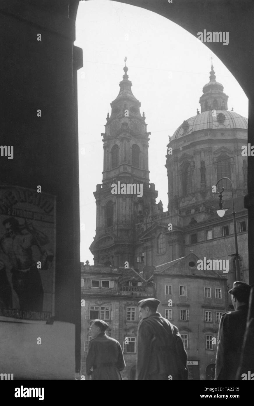 View of the St. Nicholas' Church in Prague. At the bottom of the picture, German soldiers. Since the occupation in 1939, there had been many German soldiers in the Protectorate of Bohemia and Moravia. Stock Photo