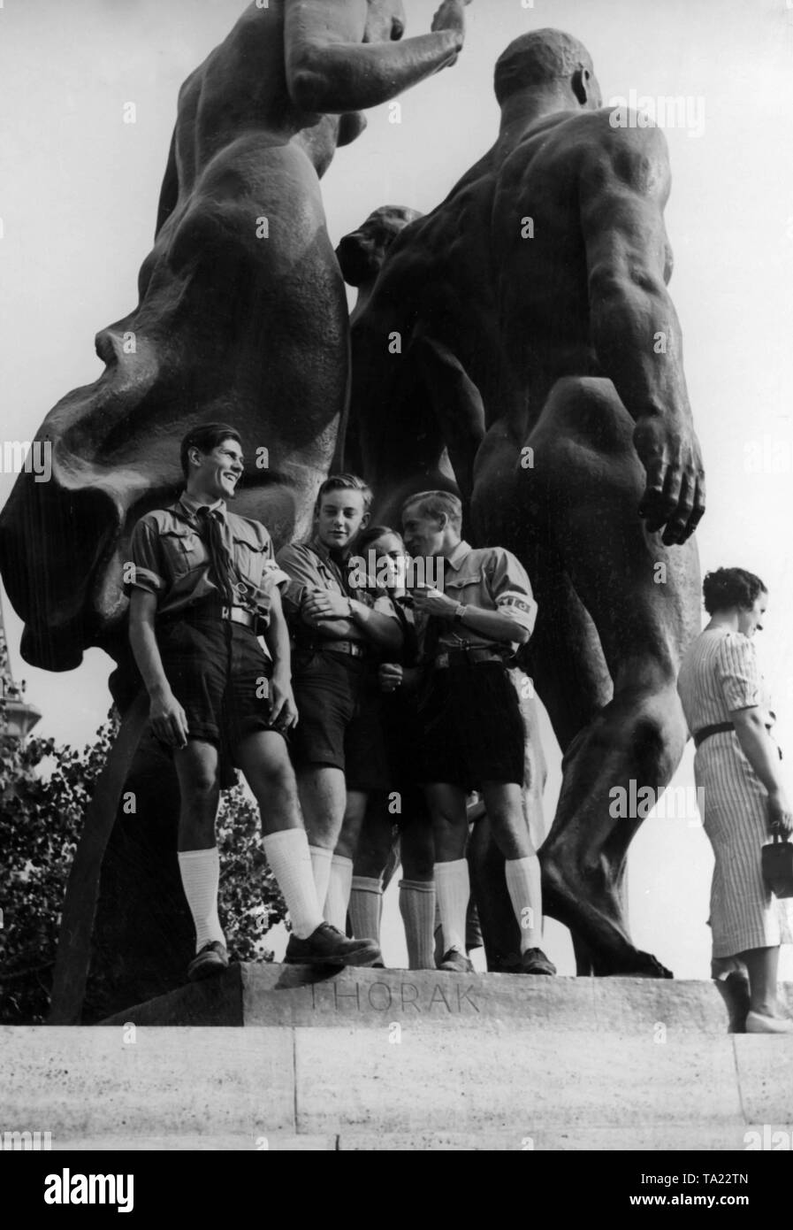 A group of teenagers in HJ uniforms pose before the German pavilion at the Paris World Fair in front of a monumental statue by the sculptor Josef Thorak. Stock Photo