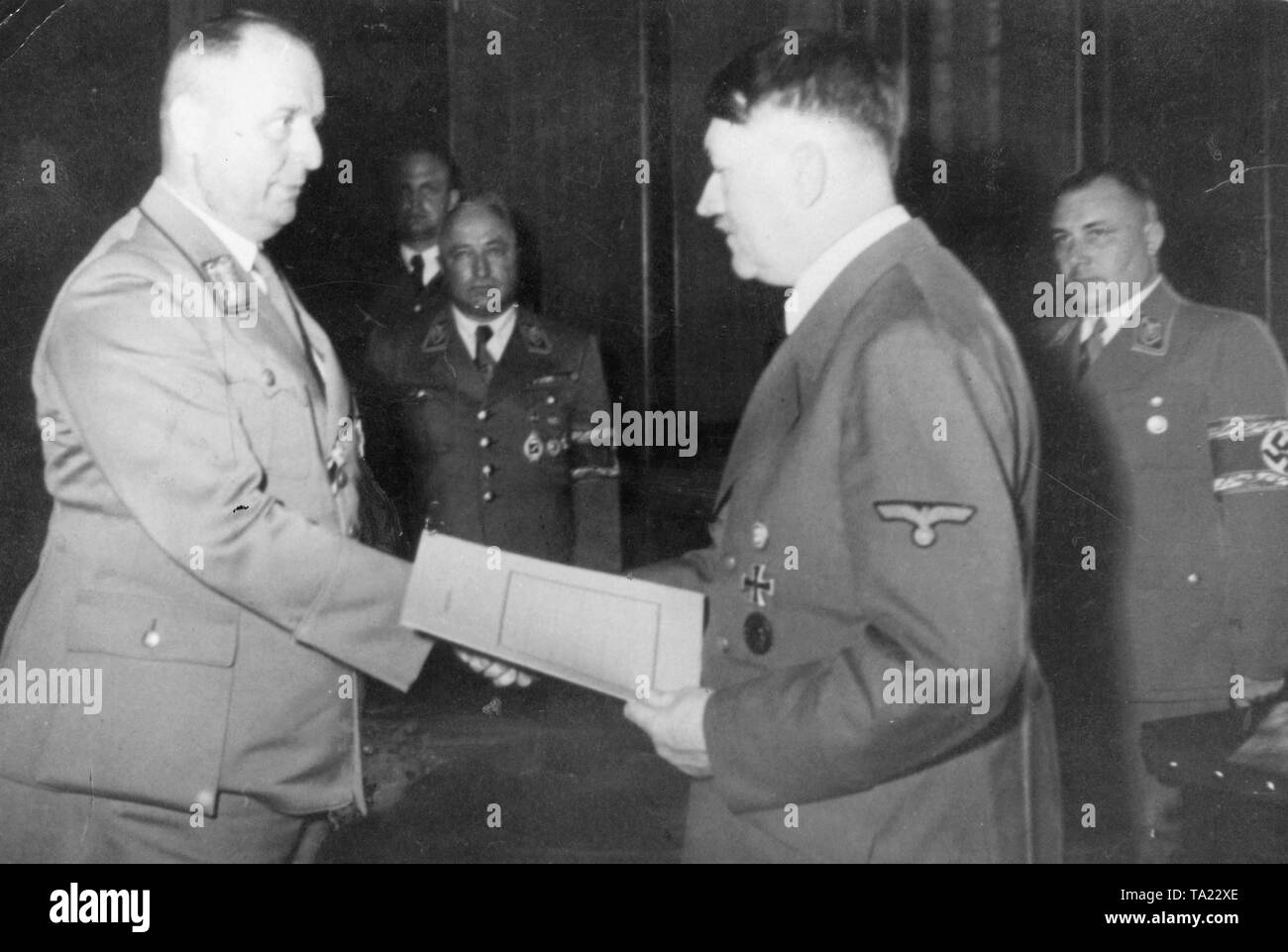Recorded: April 19.1944. Gauleiter of the Gau Munich-Upper Bavaria Paul Giesler (left) awarded by Adolf Hitler at the Chancellery in Berlin, Germany. On the right Martin Bormann Stock Photo