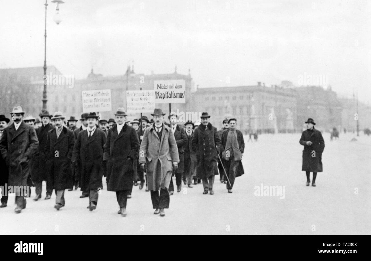 Demonstration of a Berlin tenant association. The slogan on the right-hand poster reads: 'Down with capitalism.' Next to the demonstration is a passer-by watching the men. Stock Photo