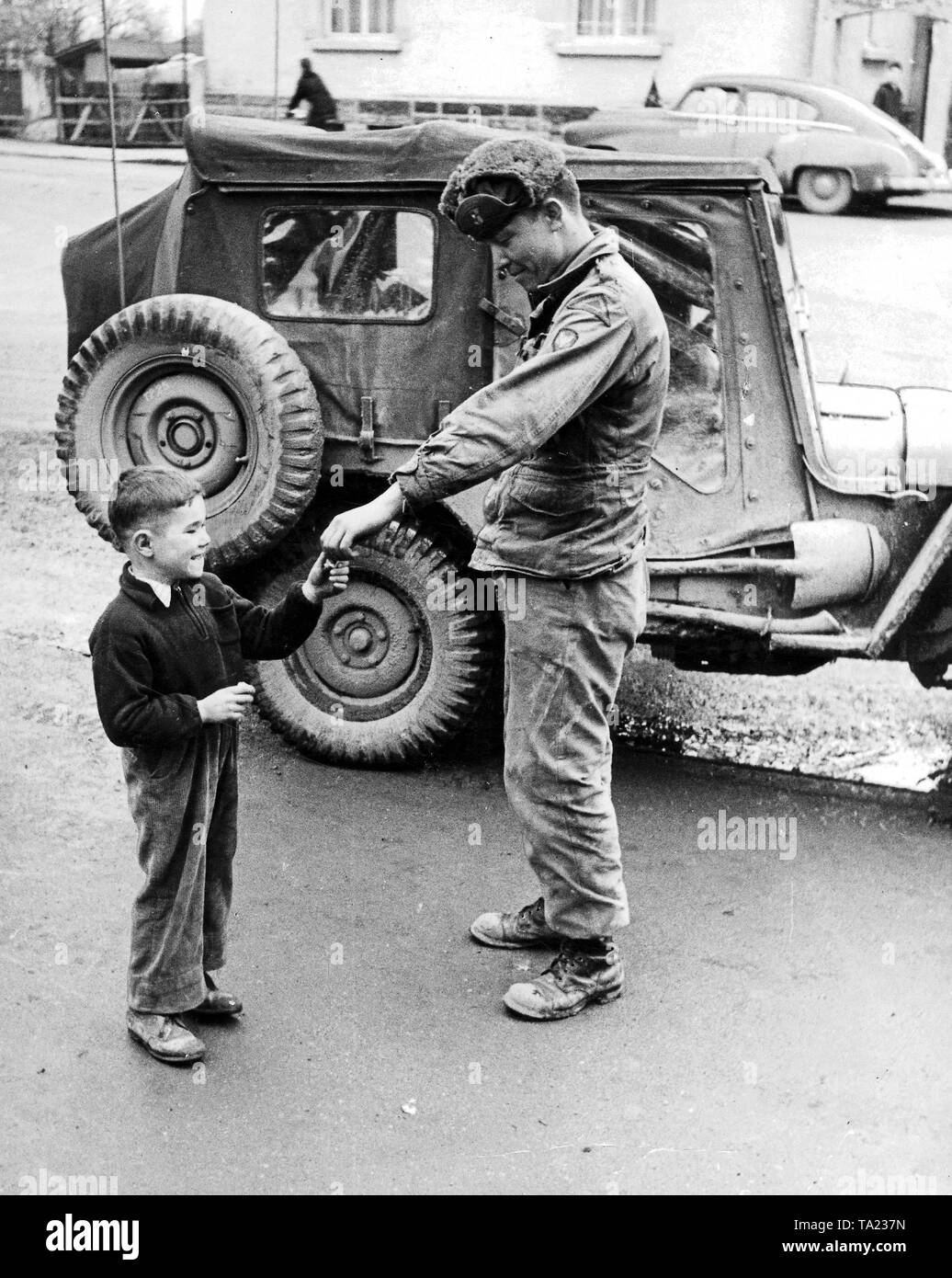 An american solider gives chocolate to a boy in occupied Germany. Stock Photo
