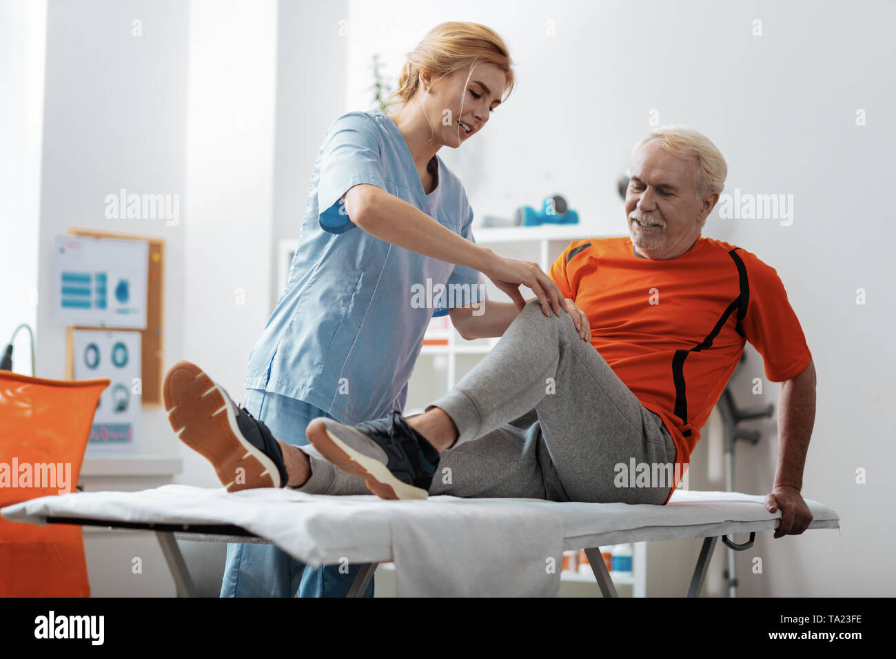 Nice blonde woman touching her patients knee Stock Photo - Alamy