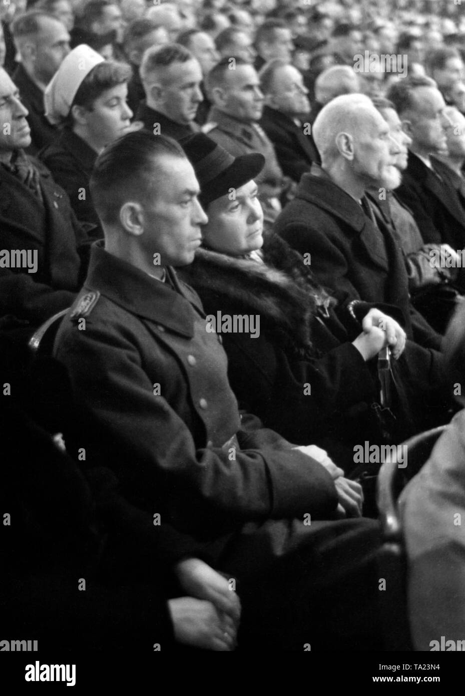 At a party rally of the NSDAP, Minister of Propaganda Joseph Goebbels gives a speech. In the audience sitting next to the party members, members of the Wehrmacht, wounded people and Red Cross nurses. Stock Photo