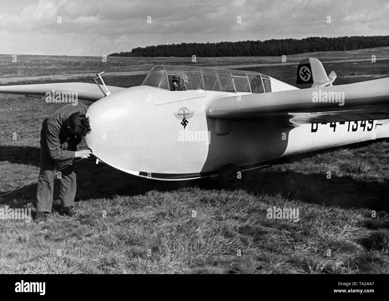 The glider 'DFS Kranich' is made ready for being pulled with a rope. The photo was taken during a course at the gliding school of the National Socialist Air Corps Group 4 (Berlin-Brandenburg region) on the Fugplatz Schoenhagen (Schoenhagen airfield) in Trebbin. The emblem of the NSFK is displayed on the aircraft. Stock Photo