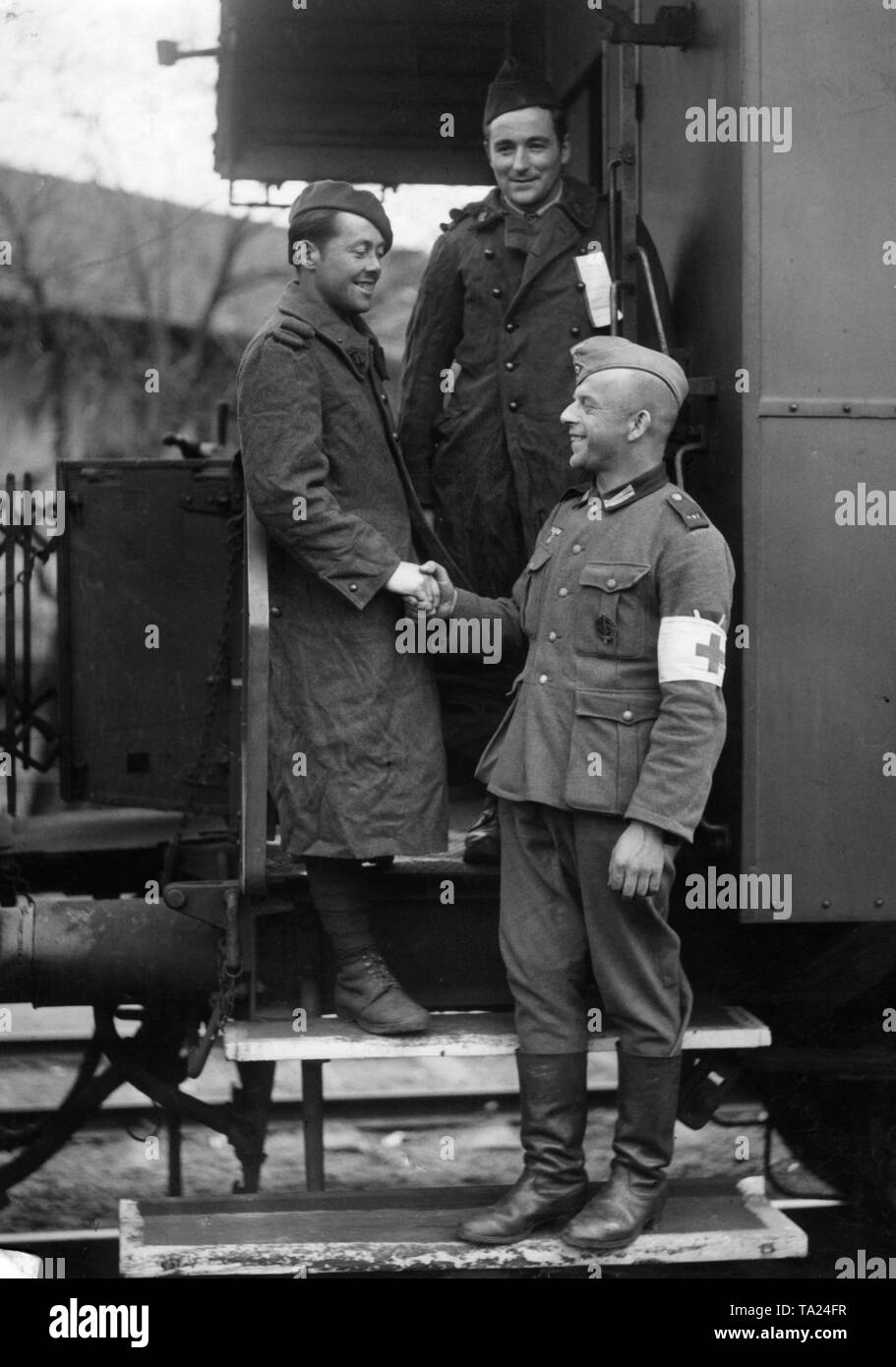 French prisoners of war, who have been released for health reasons from captivity and are now being repatriated, arrive in Chalon-sur-Saone at the Franco-German demarcation lines. A German paramedic shakes hands here in farewell. On the chest is clearly visible the SA Sports Badge. Stock Photo