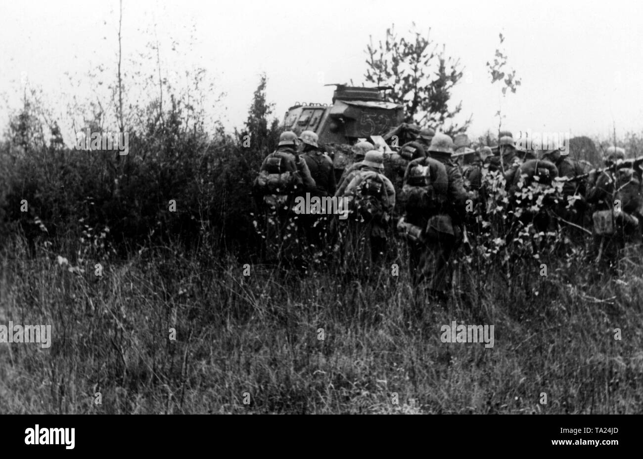 Several infantrymen are waiting in the cover of a battle tank (presumably Panzer III) for further orders. Photo of the Propaganda Company (PK): war correspondent Mauch. Stock Photo