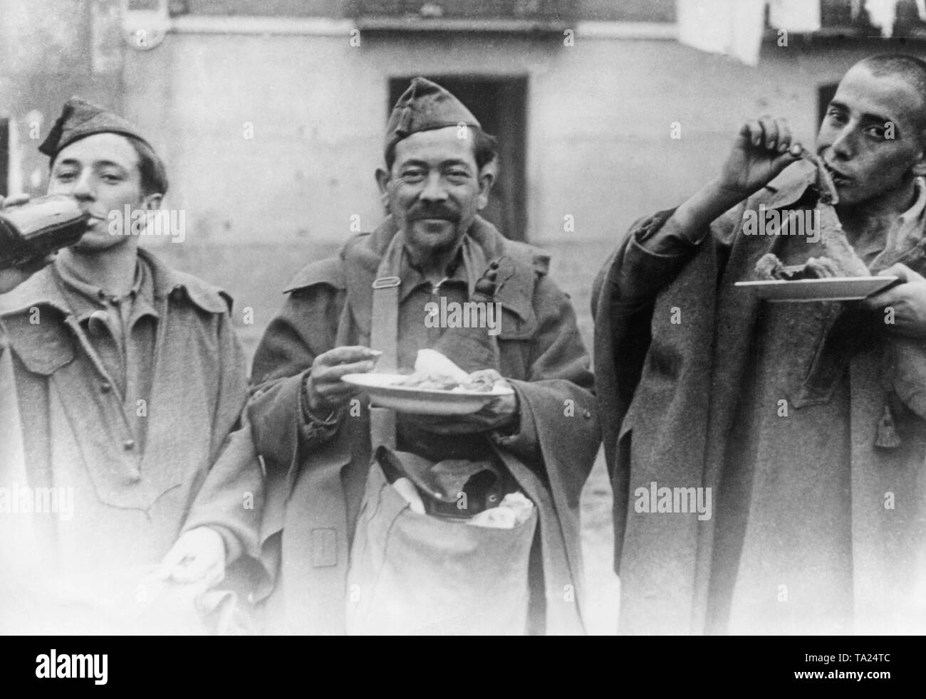 Photo of three fighters of the Spanish national faction eating and drinking behind the lines on the Teruel Front, Aragon, Spain, on the Three Kings' Day (January 6, 1938). General Franco ordered that the soldiers at the front should be given a festive ration, which was to be distributed by Spanish national aid organizations. Stock Photo